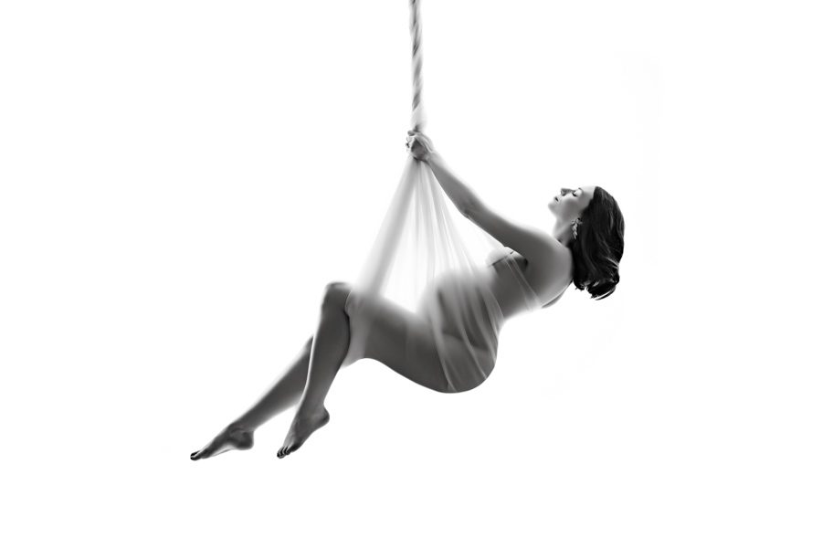 pregnant women silhouette photo of her hanging from the ceiling on a fabric rope