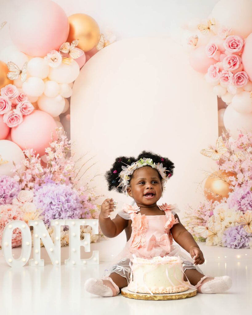 Indoor Cake Smash Photography Dallas Featuring A Colorful Balloon Backdrop For A Baby'S First Birthday Session.