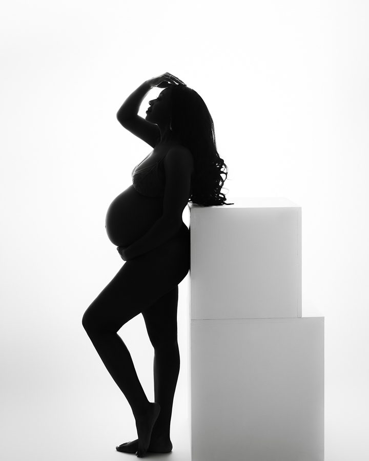 silhouette maternity photo woman leaning against white box props