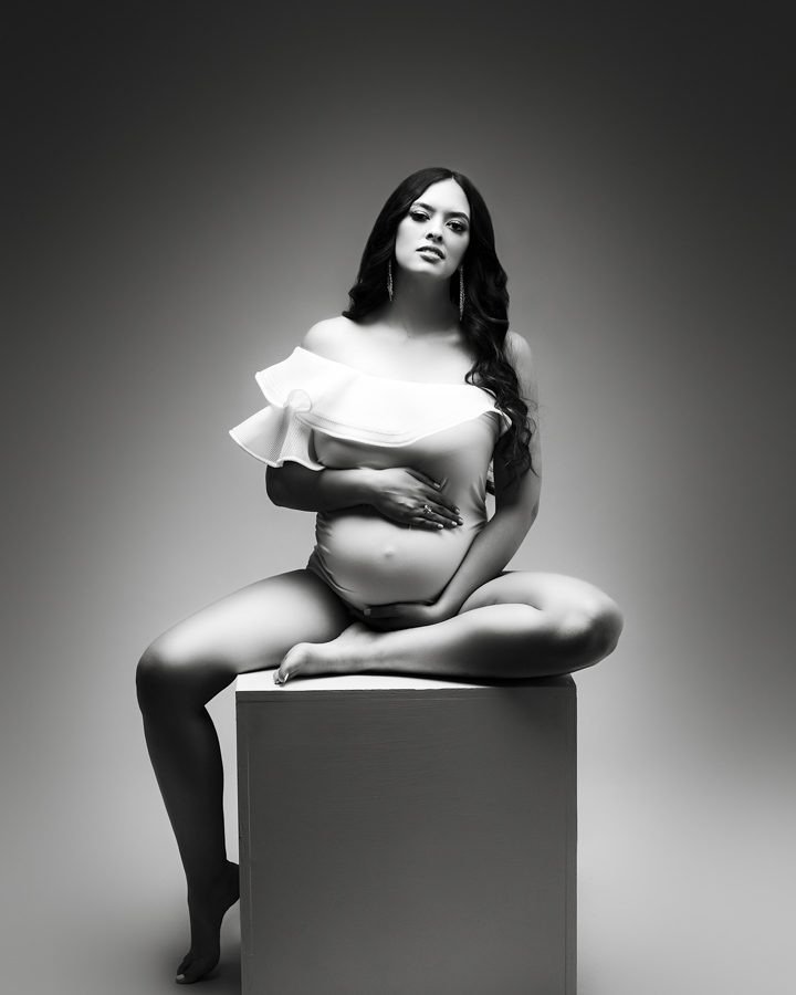 maternity photo woman sitting on cube looking at camera