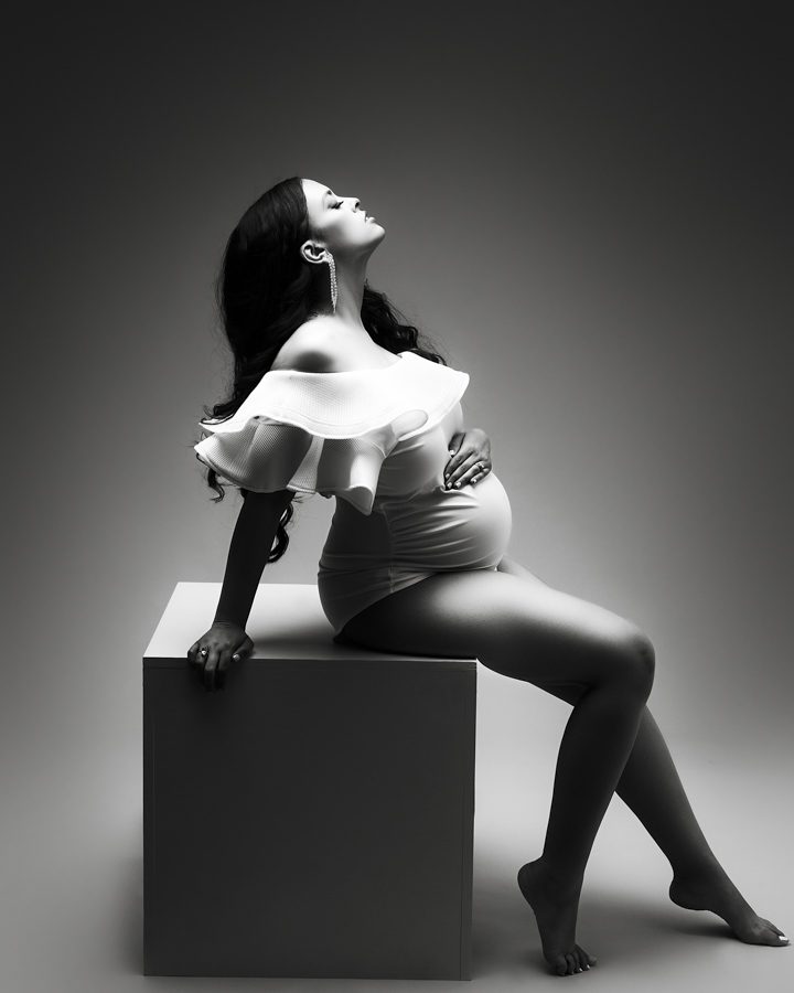 elegant maternity pose woman sitting on white cube