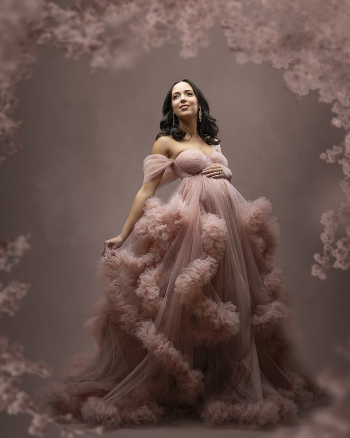 A pregnant woman in a pink gown posing for a photo.