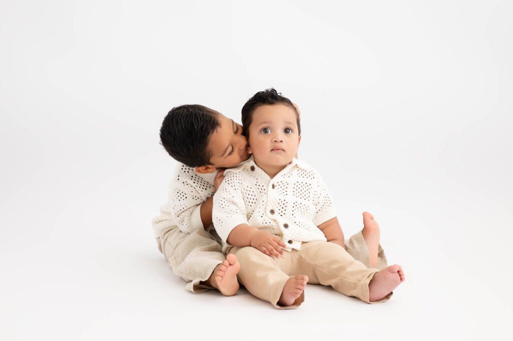 Why Include Siblings In Your Cake Smash Session? 21 Big Brother Hugging His Baby Sibling Before A First Birthday Cake Smash Session.
