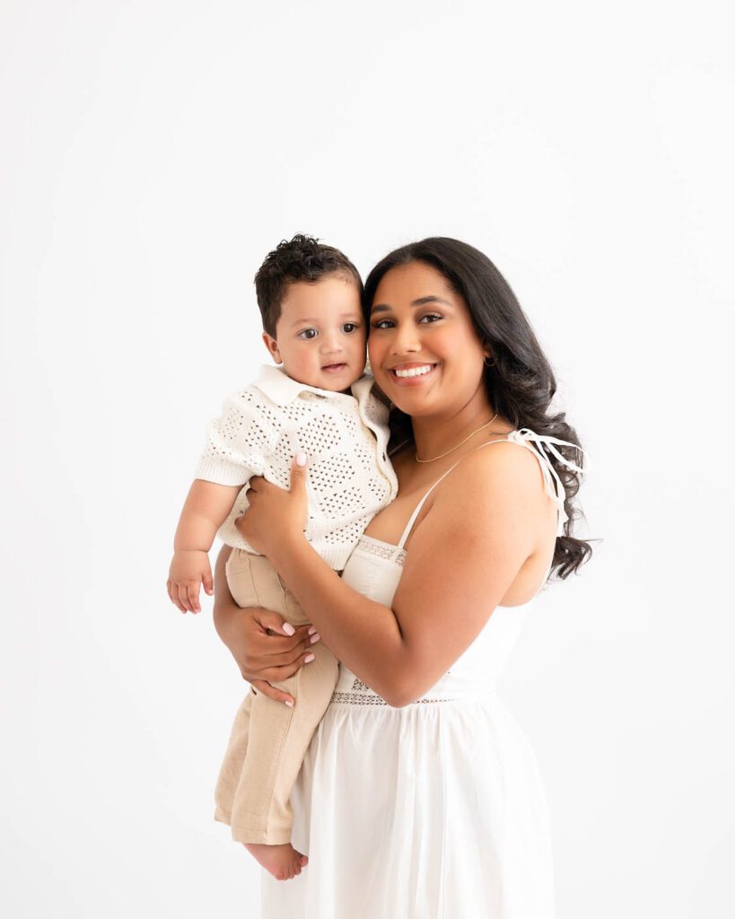 Why Include Siblings In Your Cake Smash Session? 14 Mother Holding Her One-Year-Old During A Timeless First Birthday Photography Session.