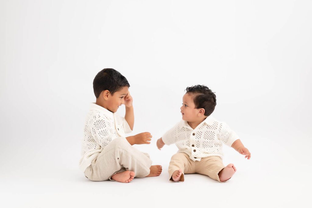 Why Include Siblings In Your Cake Smash Session? 13 Two Brothers Interacting Naturally During A First Birthday Portrait Session Before The Cake Smash.
