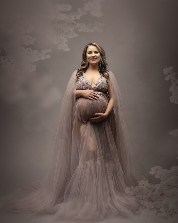 woman posed in mauve maternity gown smiling at camera