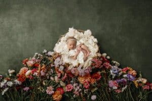 Newborn Baby Peacefully Sleeping In A Basket Surrounded By A Array Of Colorful Flowers During A Newborns First Photoshoot