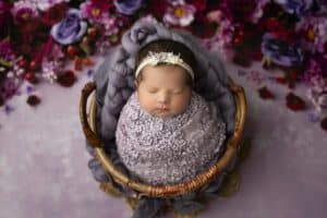 Photography For Infants Captures Newborn, Peacefully Sleeping In A Basket Surrounded By Flowers.