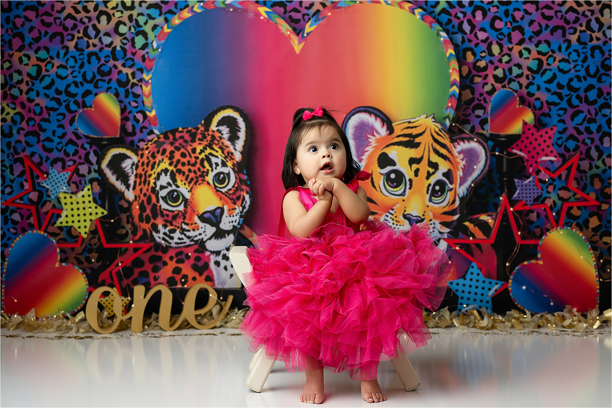 Baby In A Pink Ruffle Dress Sits In Front Of A Cake Smash Photography Setup