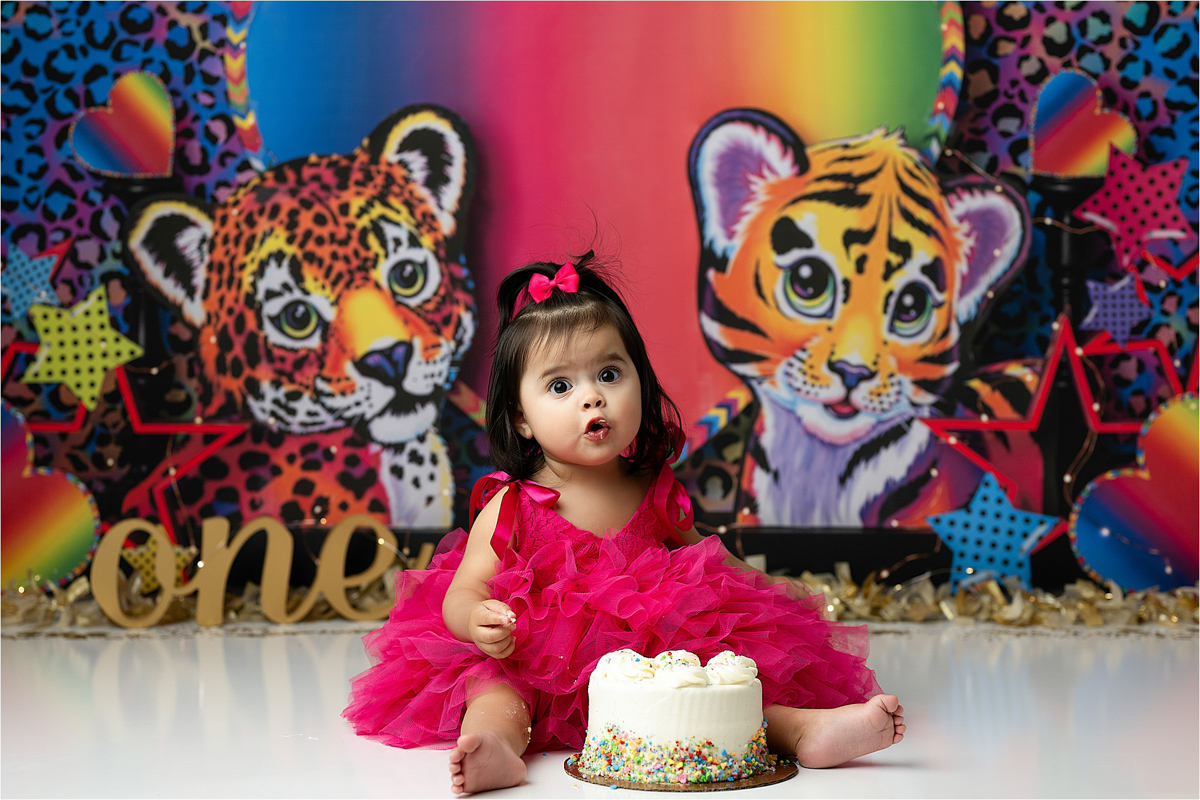 Baby Sits Smiling In Front Of A Lisa Frank Inspired Cake Smash Photoshoot