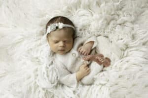 Newborn Wearing A White Knit Outfit Sleeping On A White Blanket | Pricing For Dallas Newborn Photography