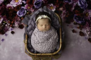 Newborn Posed In A Basket Surrounded By Purple And Red Flowers Captured By Professional Dallas Newborn Photographer | Lily Hayes Photography 