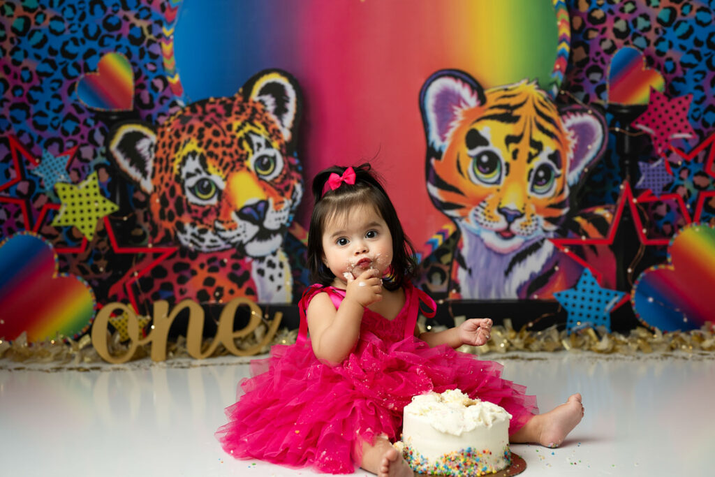 Colorful Lisa Frank Cake Smash Photography Session In Dallas Featuring Baby Girl With Rainbow Themed Birthday Setup