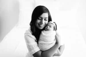 Mother-Holding-Sleeping-Newborn-Close-To-Face-Smiling-For-Affordable-Newborn-Photographer-In-Dallas