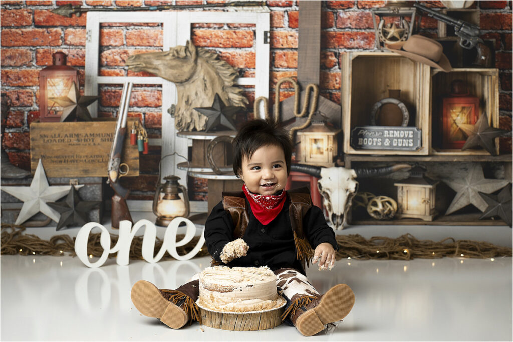 Baby Covered In Cake Smiling During Their Cowboy Cake Smash Photoshoot.