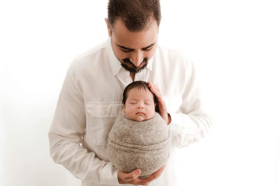 Booking A Dallas Newborn Photographer: What Every Parent Should Know 15 Father Holding Newborn Baby During Luxury Newborn Photography Session In Dallas
