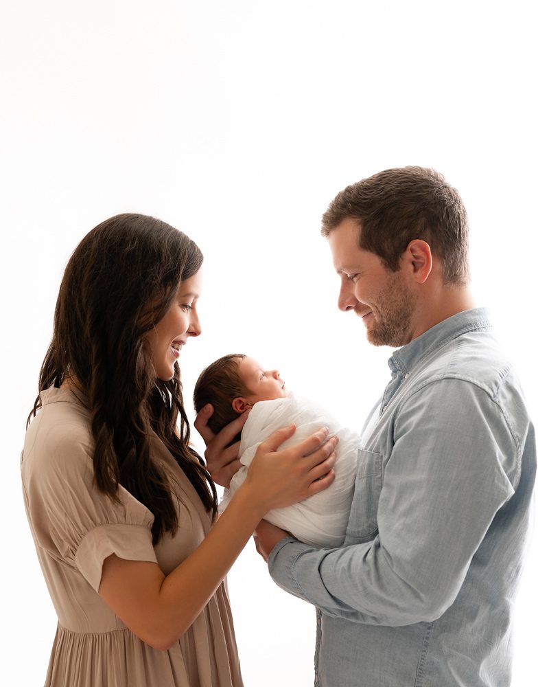 Parents Smiling Down A Baby For Dallas Newborn Photography