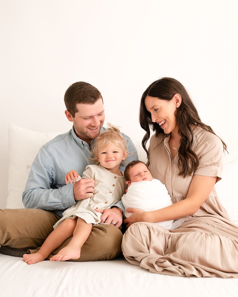Family Of Four Smiling At Baby For A Lifestyle Newborn Photoshoot Dallas