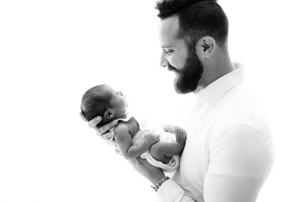 How To Start A Newborn Photography Portfolio 10 Father Holding Newborn Baby In A Black And White Portrait Showing Connection And Scale