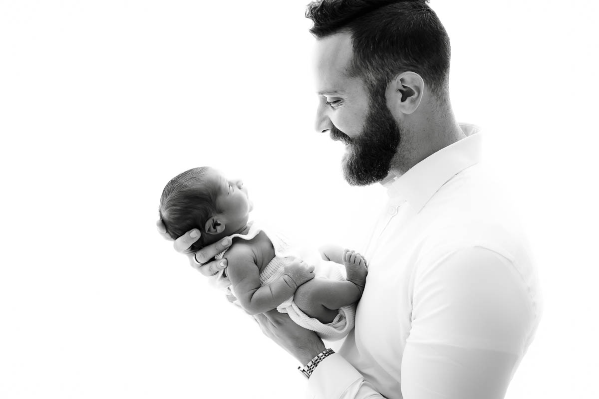 Father Holding Newborn Baby In A Black And White Portrait Showing Connection And Scale