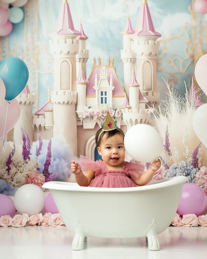 Toddler In A Pink Dress Sits In A Mini Bathtub For A 1St Birthday Cake Smash Photoshoot