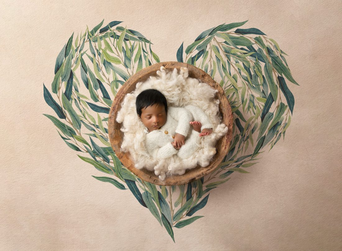 Baby Sleeps Peacefully In A Bowl Surrounded By A Heart-Shaped Leafy Design By Newborn Photography Dallas