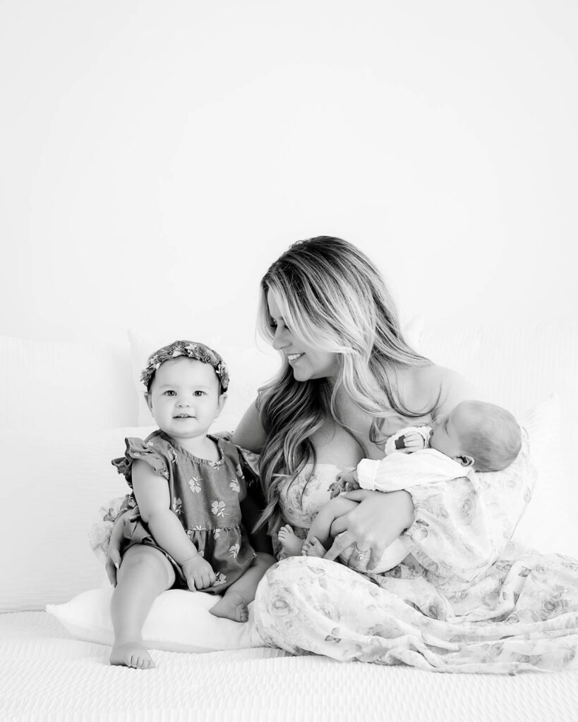 Mother Sitting With Newborn Baby And Toddler During Newborn Family Photography Session In Dallas