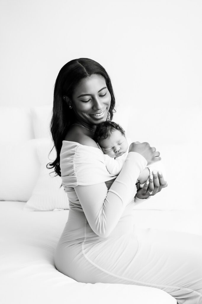 mom smiling while holding a sleeping baby against her chest for lifestyle newborn photography