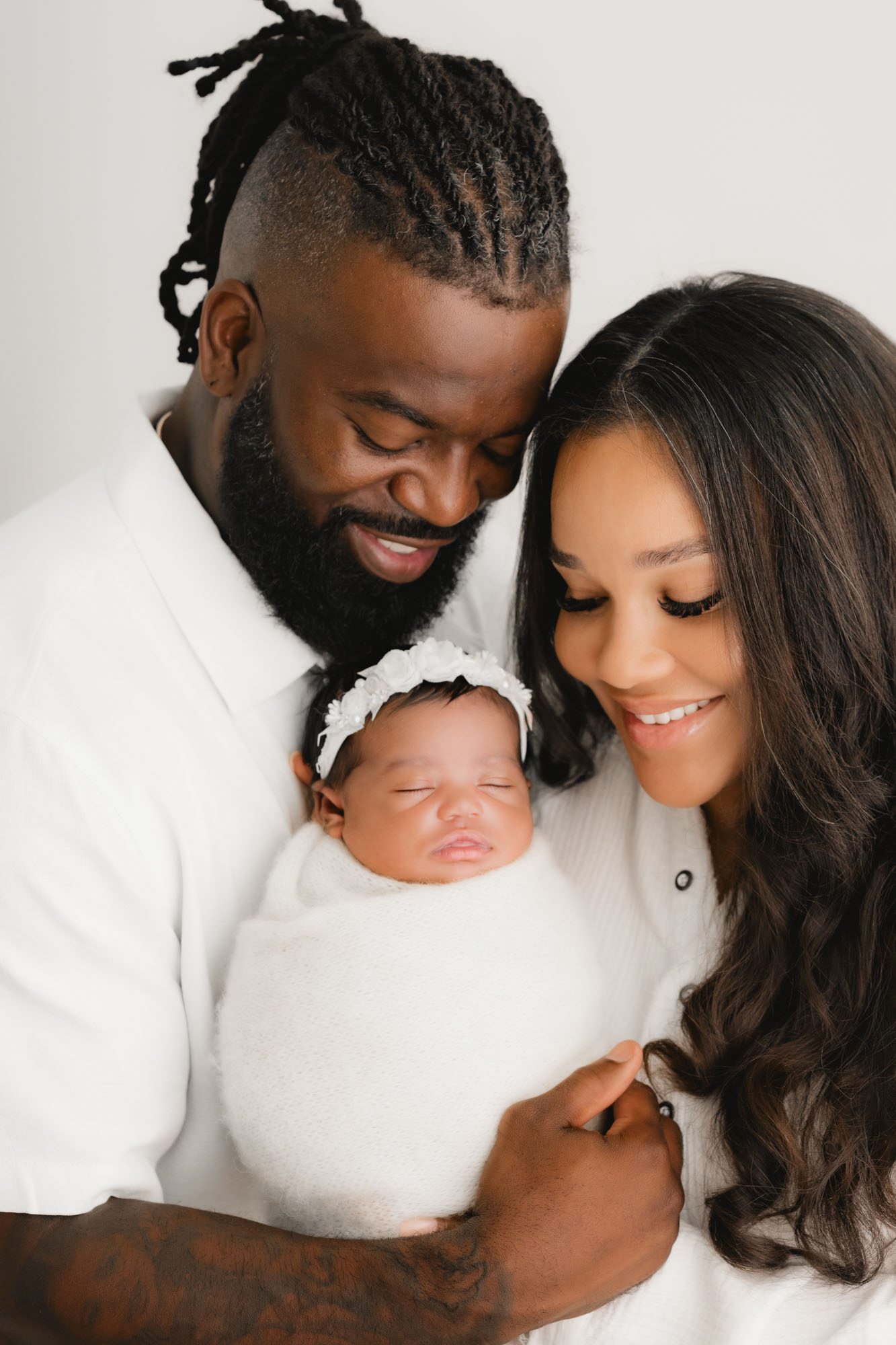 Dallas Family Newborn Photographer Captures Parents Smiling With Swaddled Baby Girl
