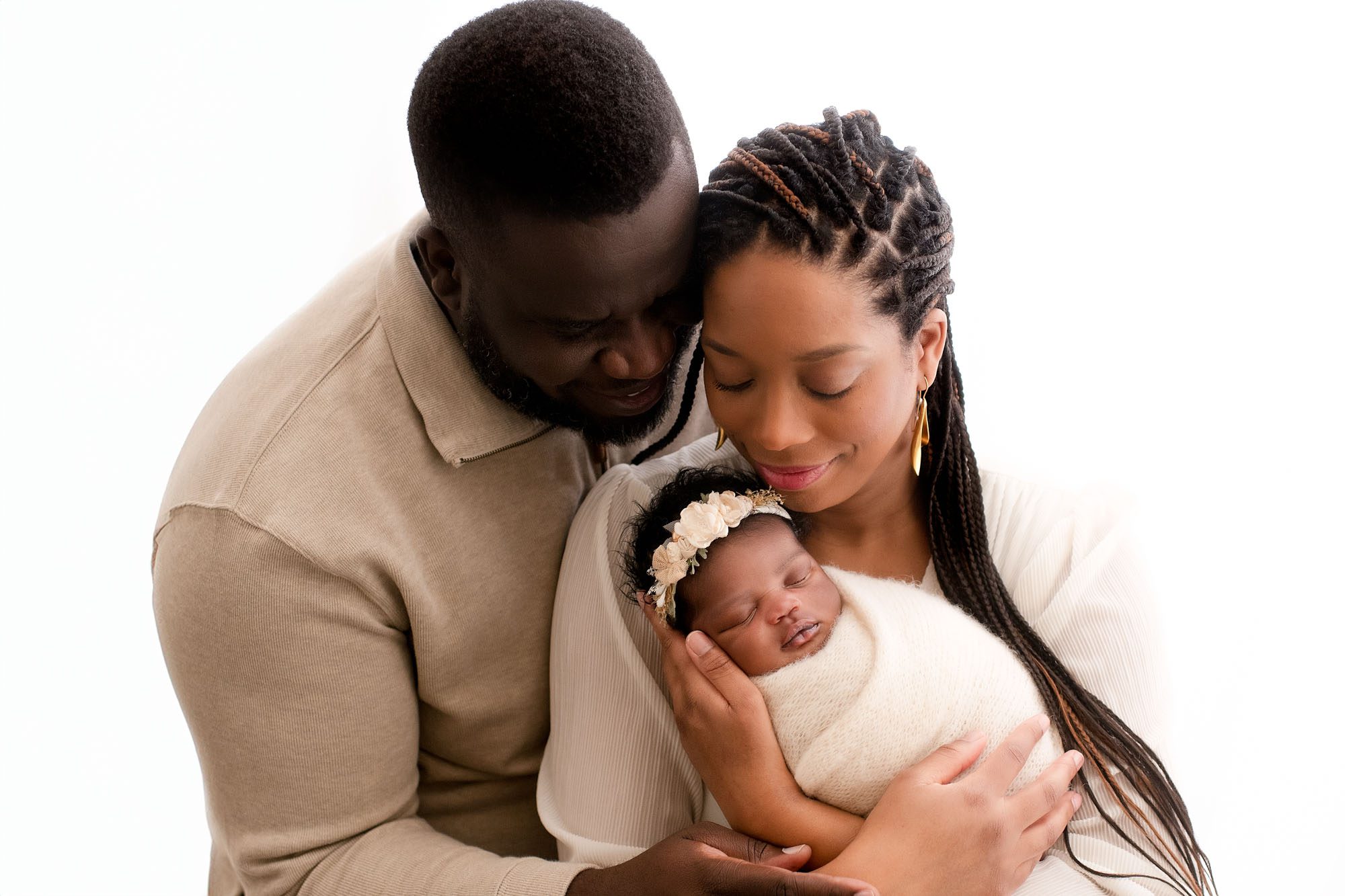 Family Portraits Of Parents Holding Their Newborn Baby Wrapped In Cream Swaddle In Dallas Newborn Photographers Studio