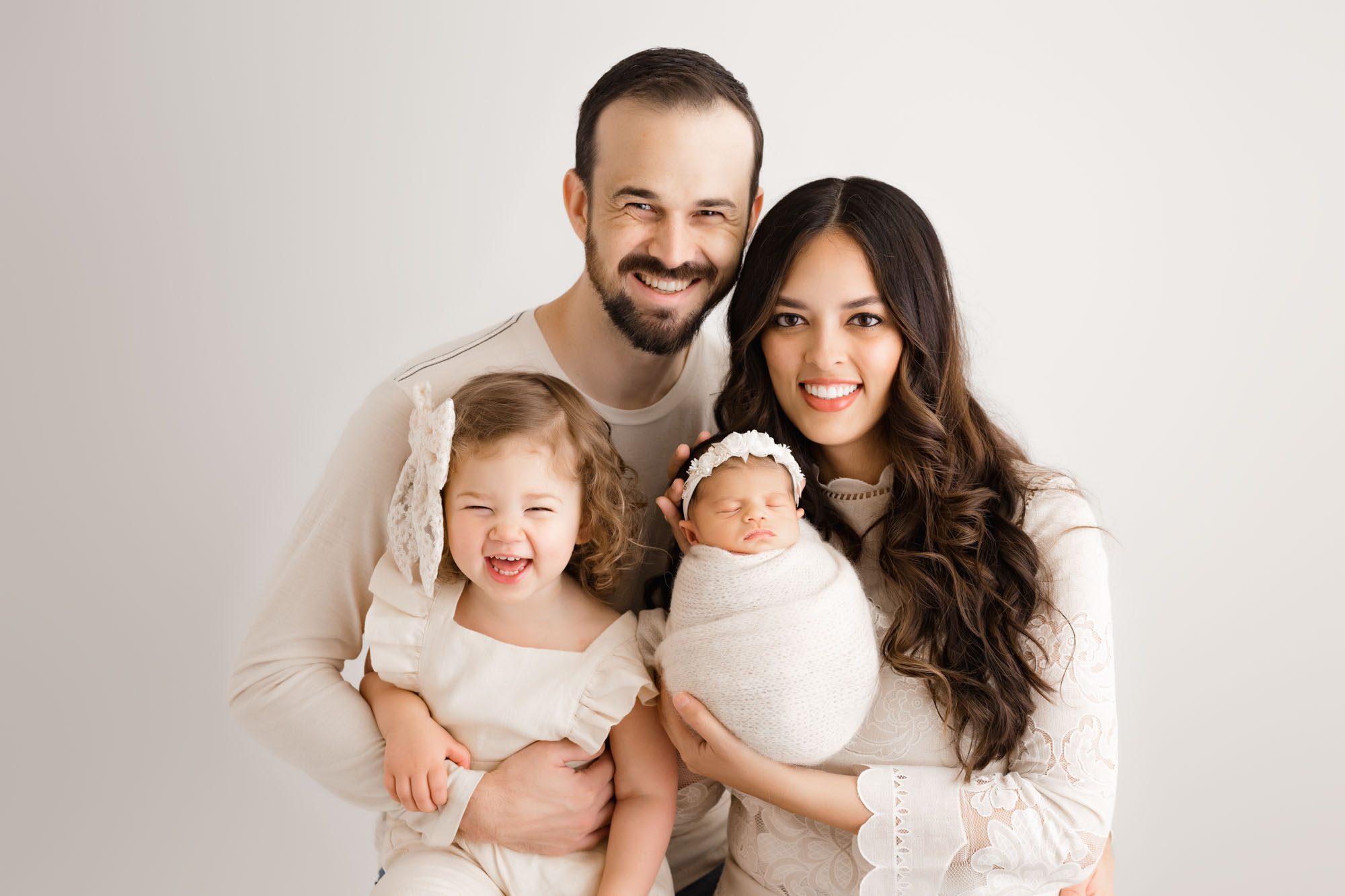 Happy Family With Toddler Sister And Newborn Baby Swaddled In Cream Wrap During Dallas Lifestyle Newborn Pictures