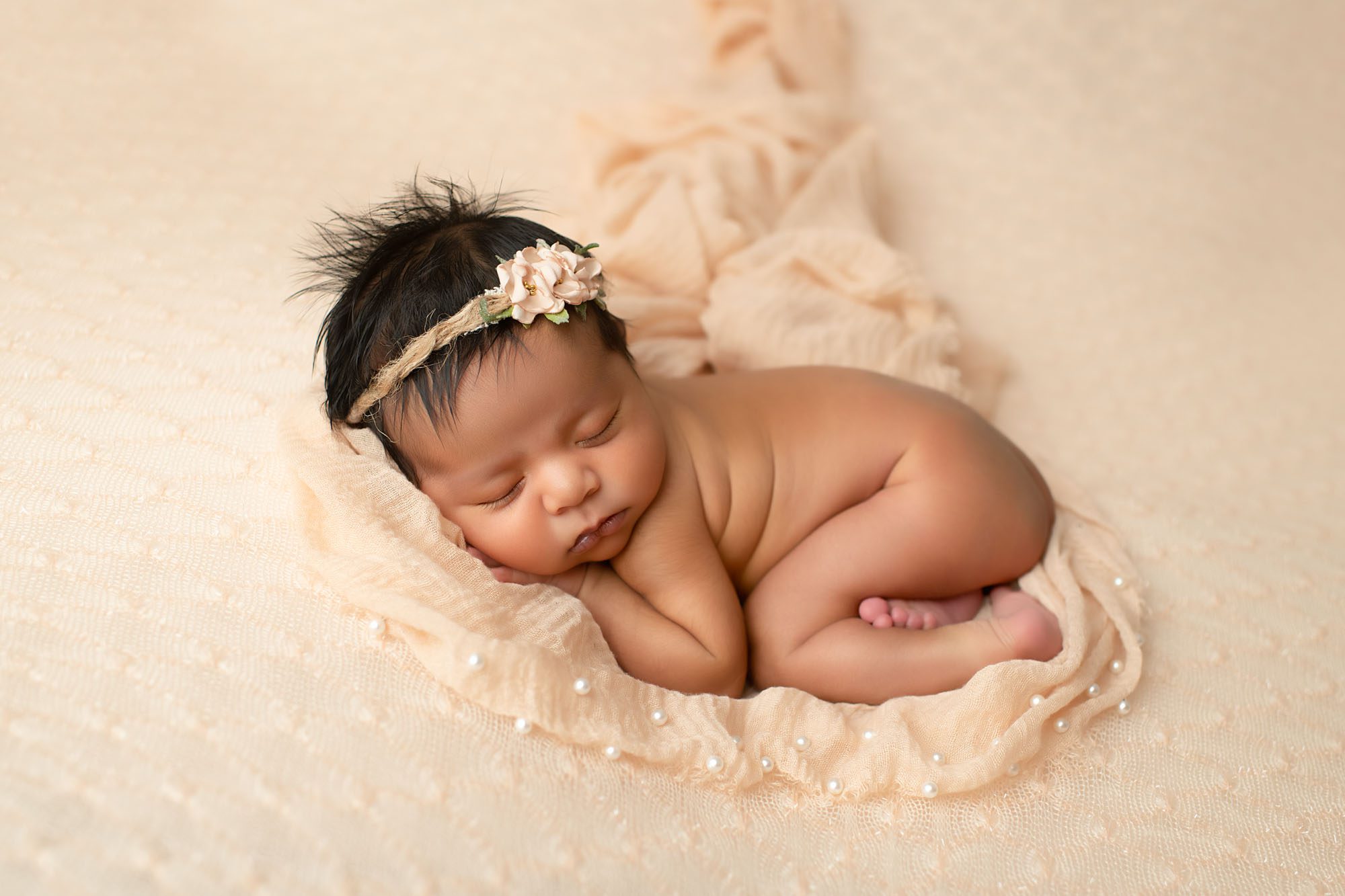 Lifestyle Newborn Photography | Capturing Authentic Moments 1 Newborn Baby Girl Curled Up On Peach Blanket During Professional Newborn Photography In Dallas