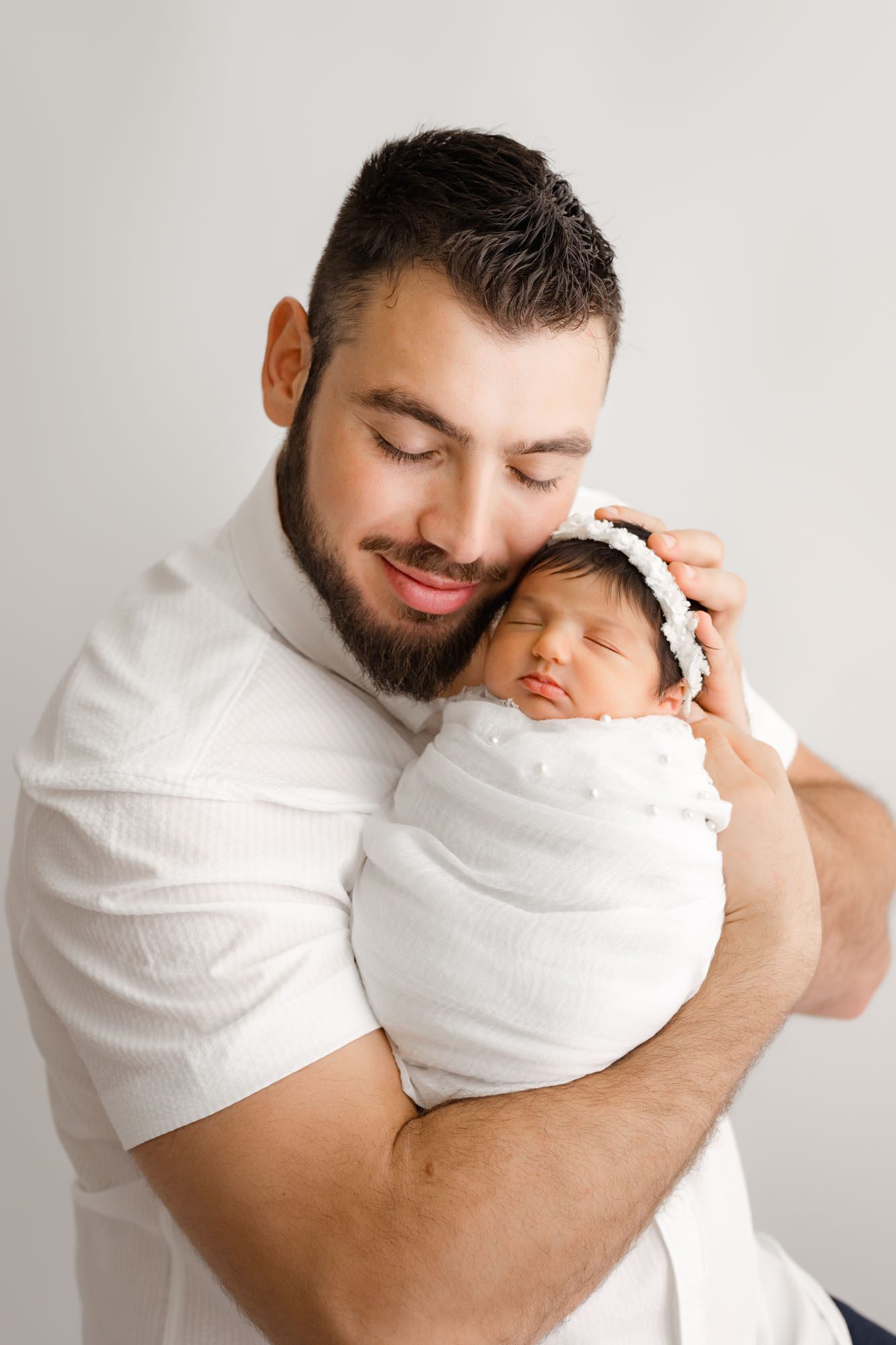 Lifestyle Newborn Pictures Capture Dad Holding Swaddled Baby In White Wrap