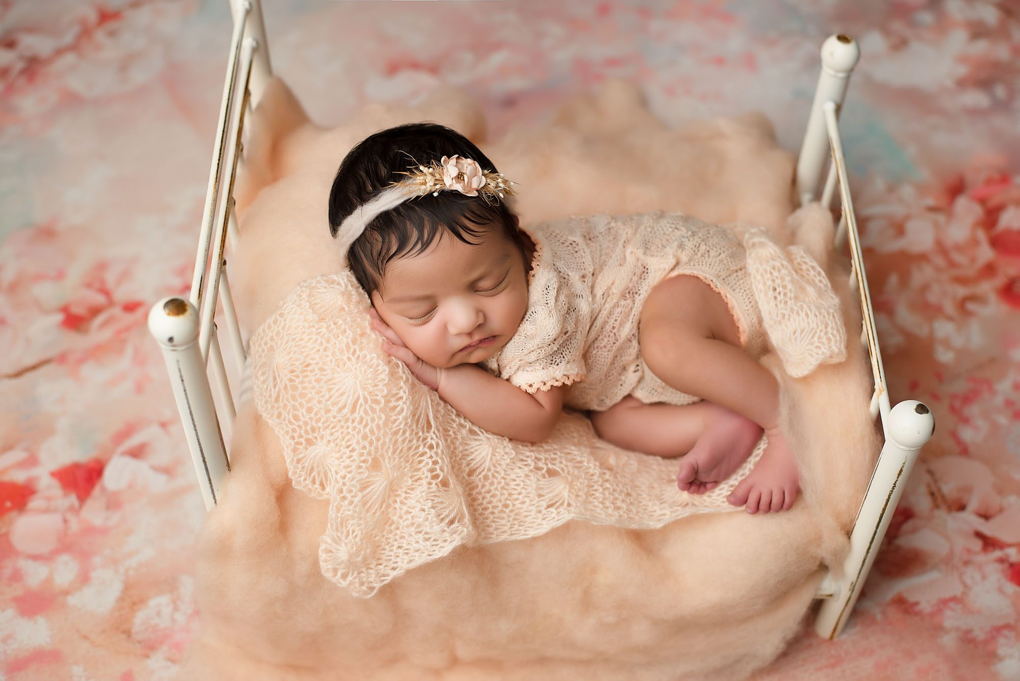 Newborn Baby Girl In Peach Knit Outfit Sleeping On White Bed During Dallas Newborn Photography Session