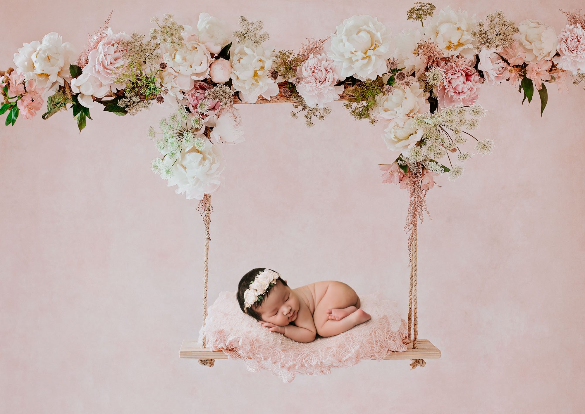 Infant Baby Girl Sleeping On A Floral Swing With Blush Pink Flowers During A Photography For Newborns Session In Dallas