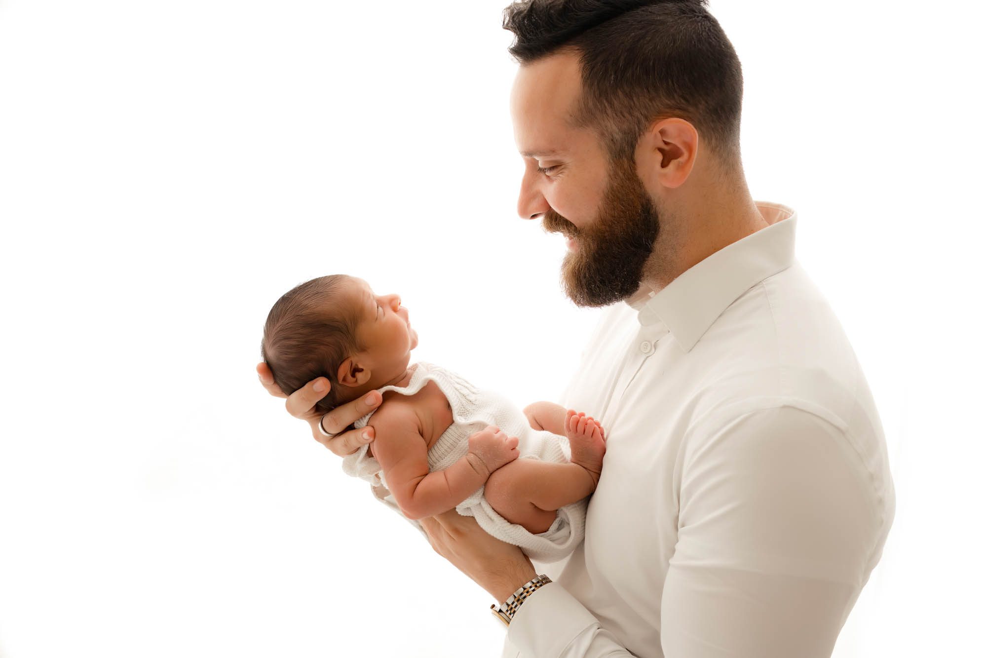 Father holding newborn baby in natural light studio portrait in Dallas for timeless newborn photography