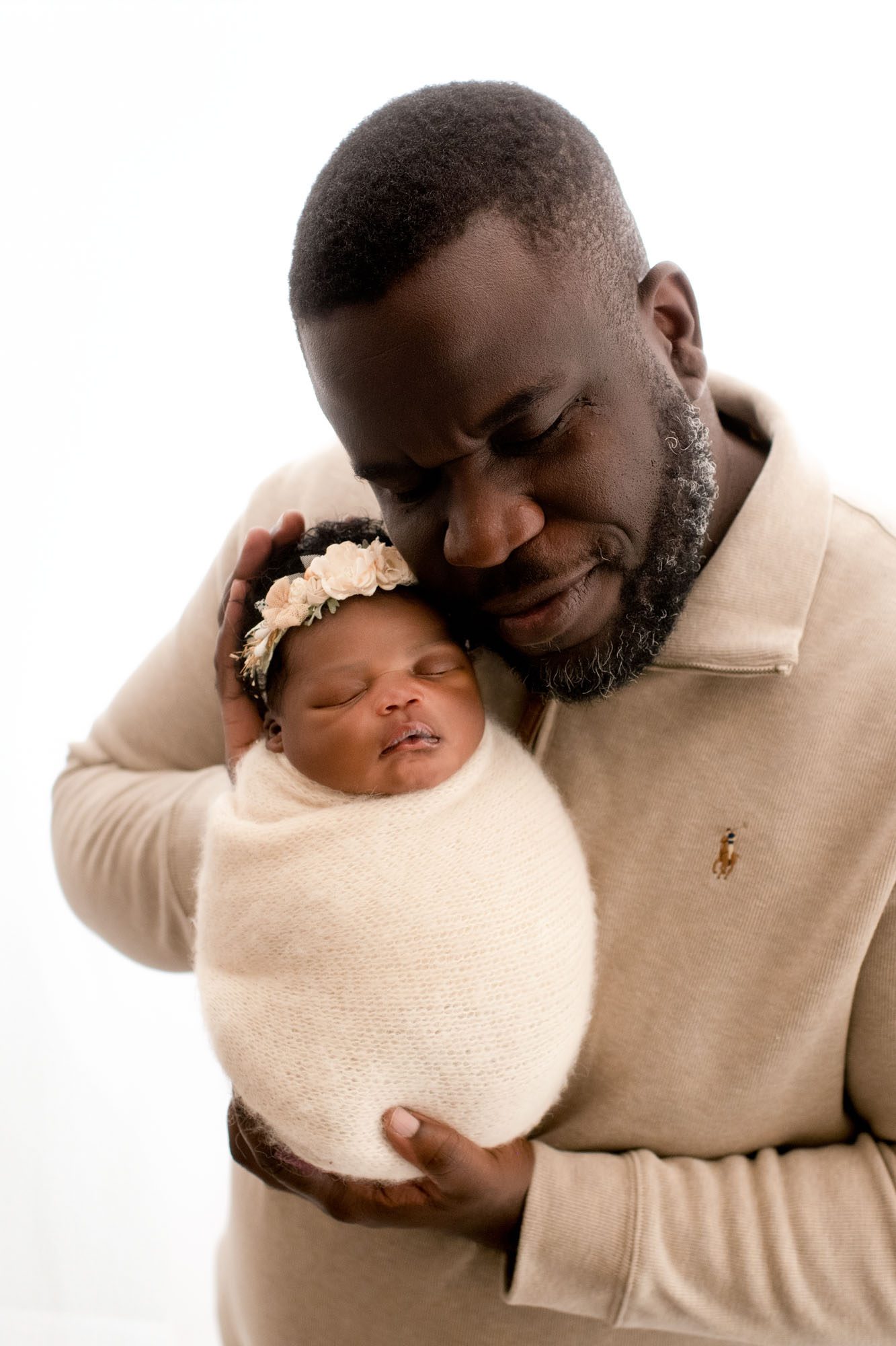 Father Gently Holding Newborn Baby In Cream Wrap During Professional Newborn Photographers Studio In Dallas