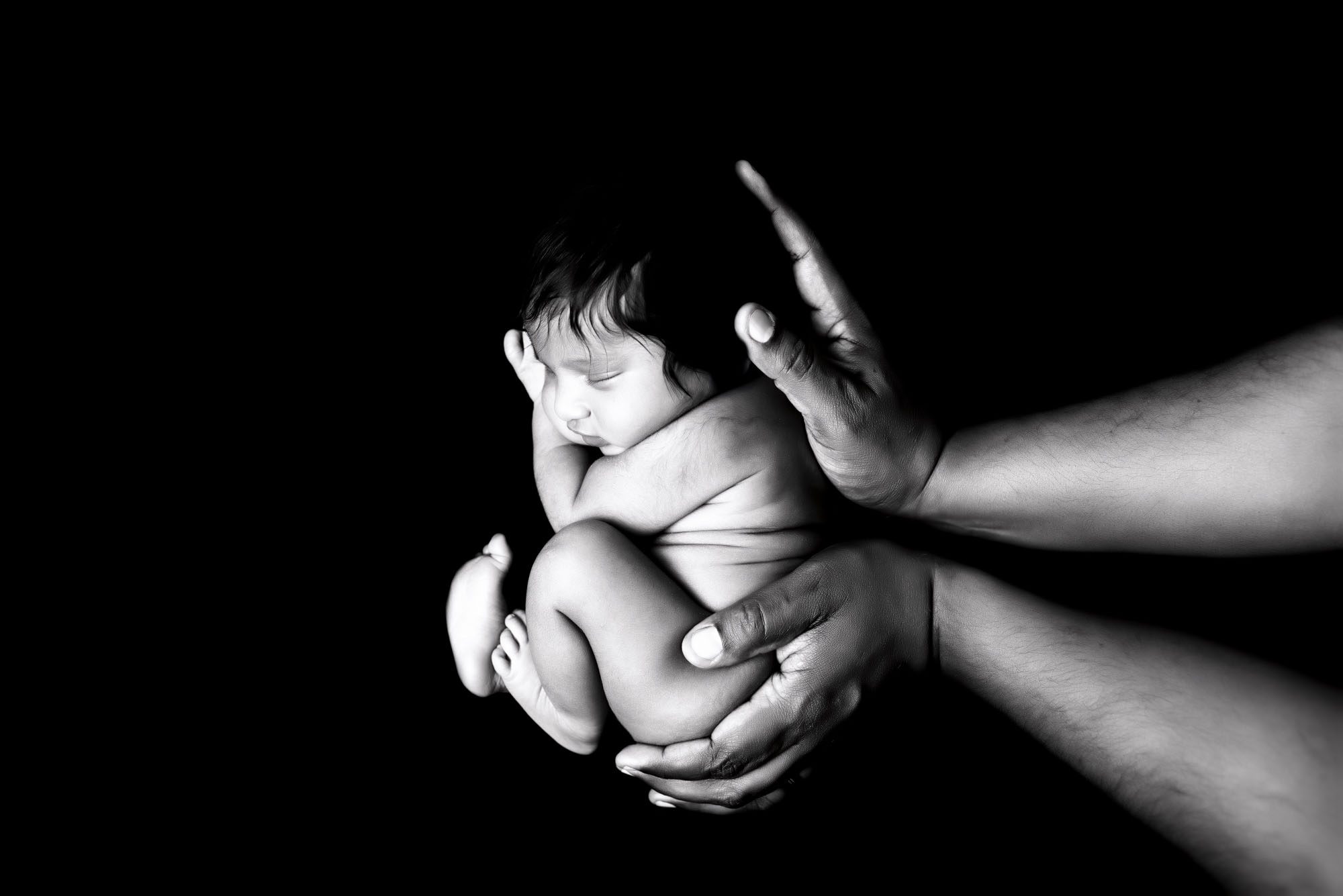 Baby Pictures | When Is The Best Time To Take Them? 2 Black And White Newborn Photo Of Baby Peacefully Curled In Father’s Hands – Newborn Photographer In Dallas