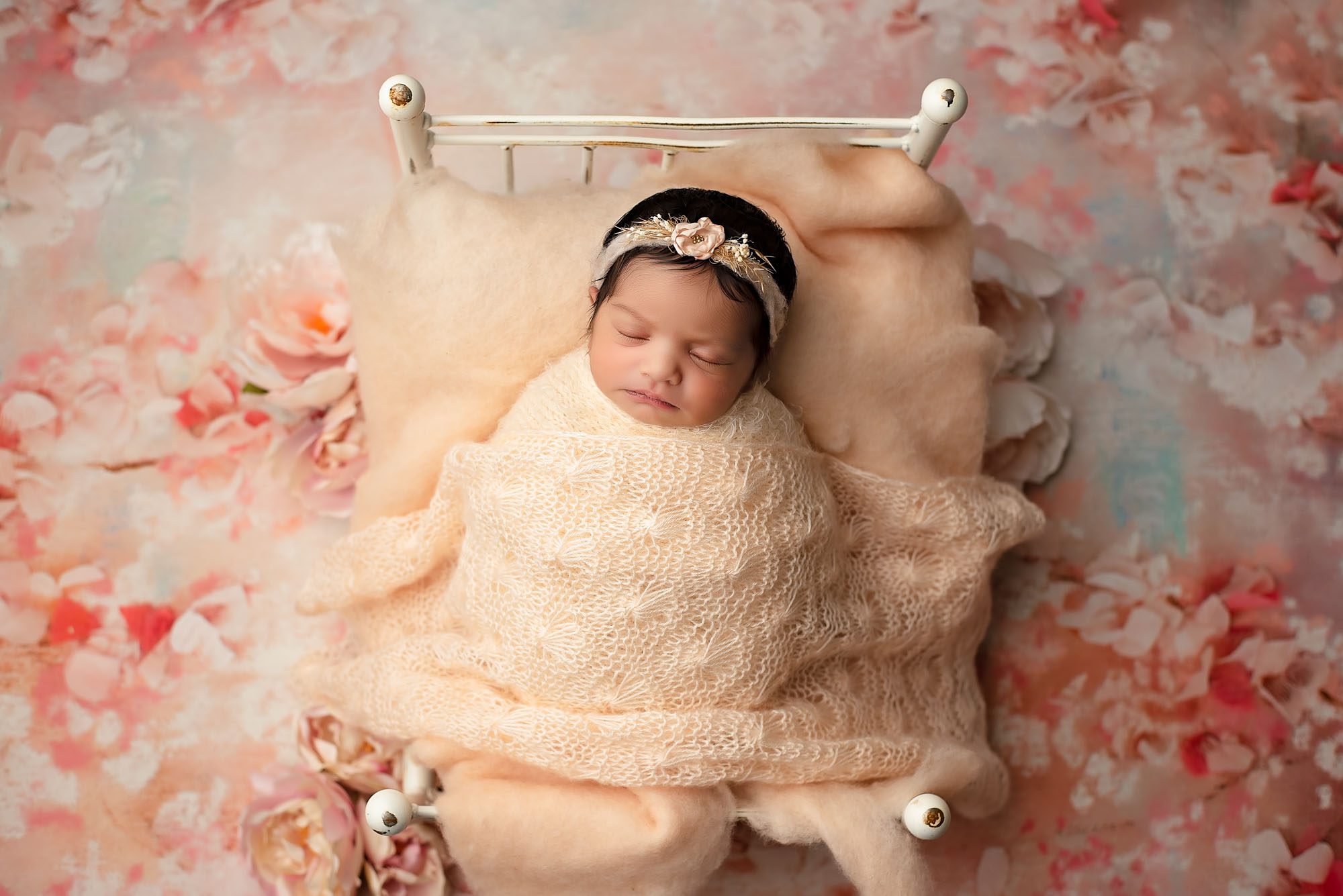 Newborn Baby Girl Sleeping In Peach Knit Wrap On White Bed During Professional Dallas Newborn Photoshoot