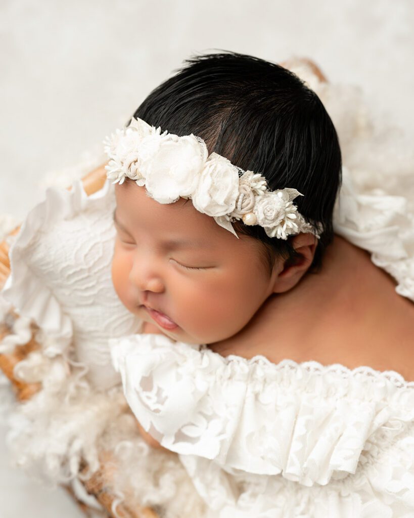What To Expect During A Newborn Photography Session In Dallas 12 Close-Up Newborn Portrait Of Baby Girl With Floral Headband In A Soft Neutral Dallas Studio