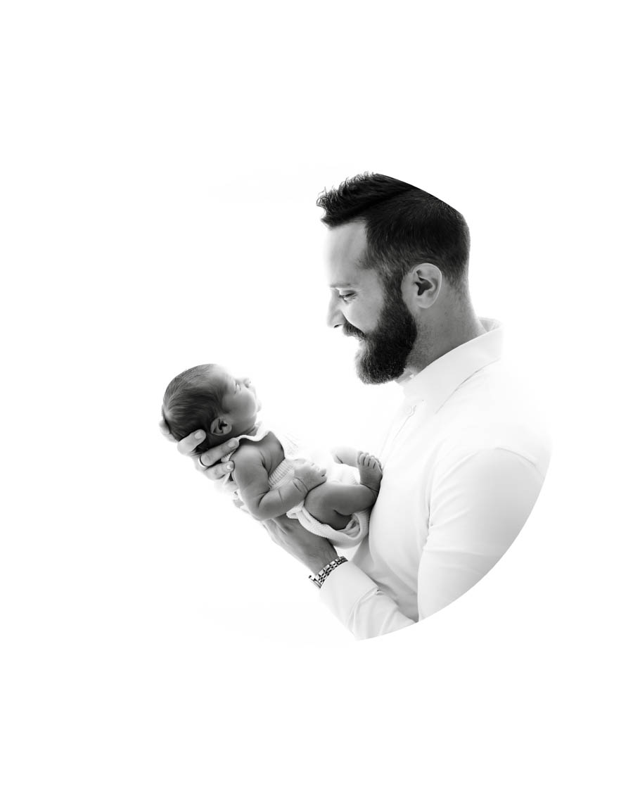 Father holding newborn baby in a soft studio portrait in Dallas Texas