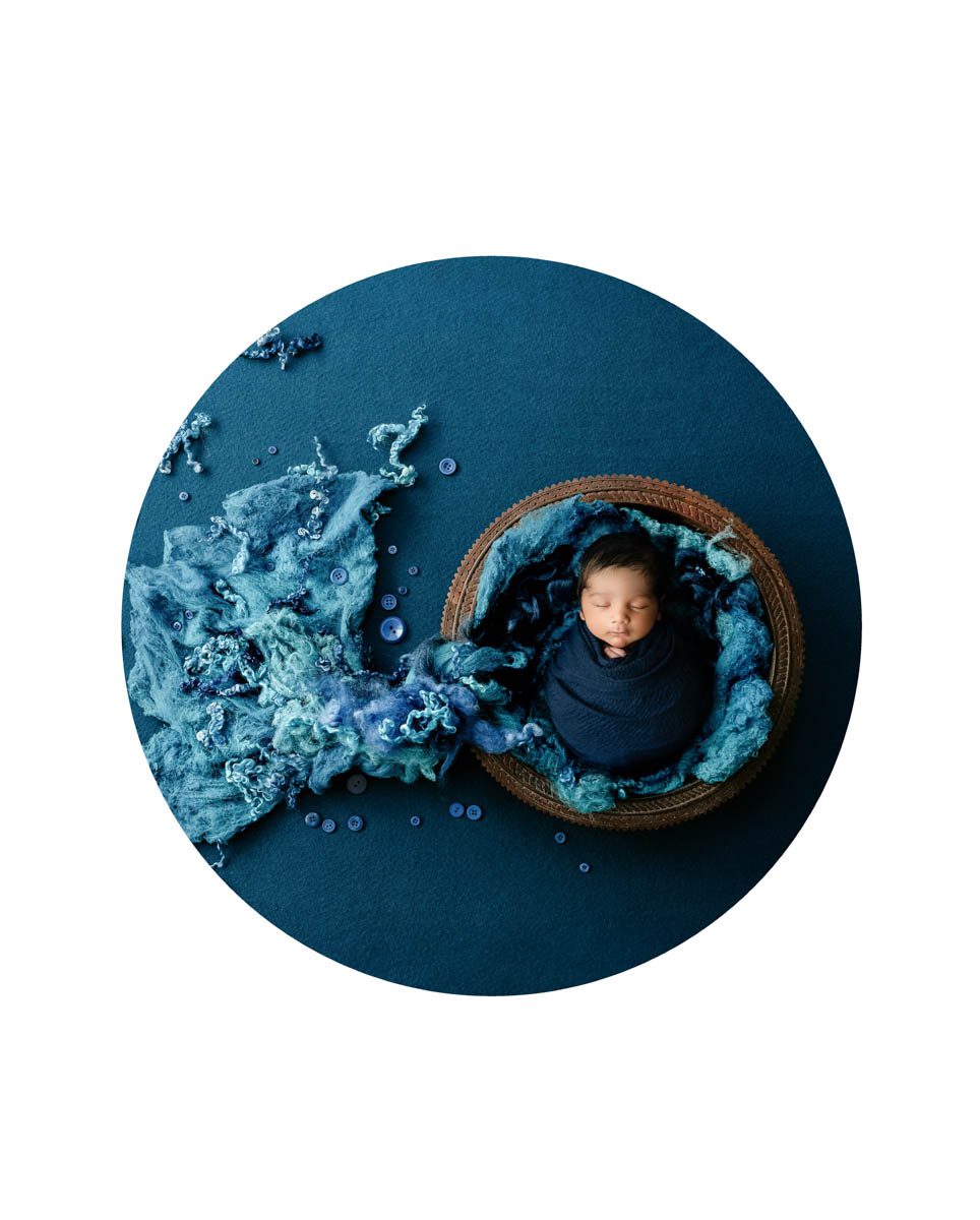 Newborn baby wrapped in deep blue tones during a fine art studio newborn photography session in DFW