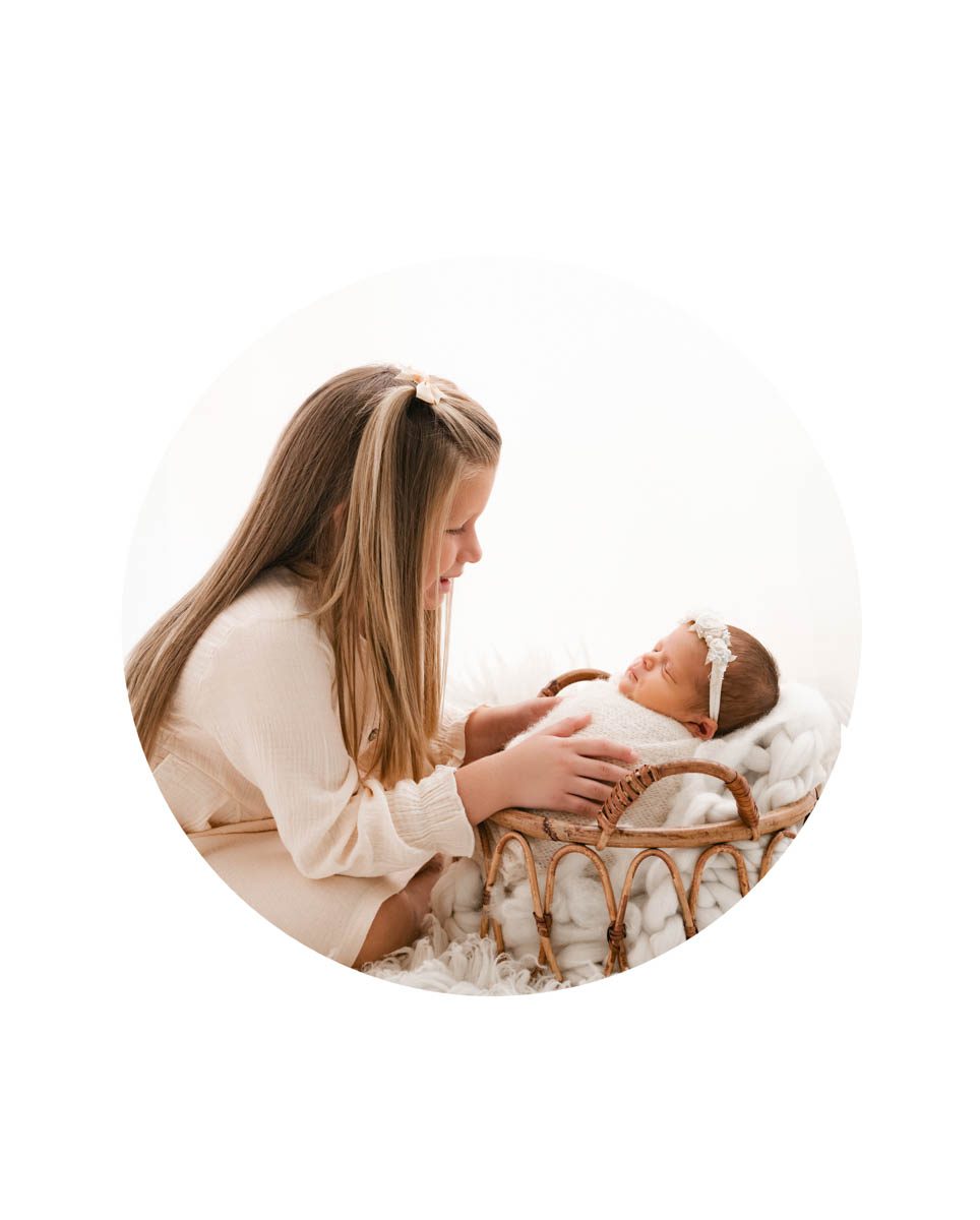 sibling interacting with her newborn baby sister during a lifestyle newborn photography session in a DFW studio
