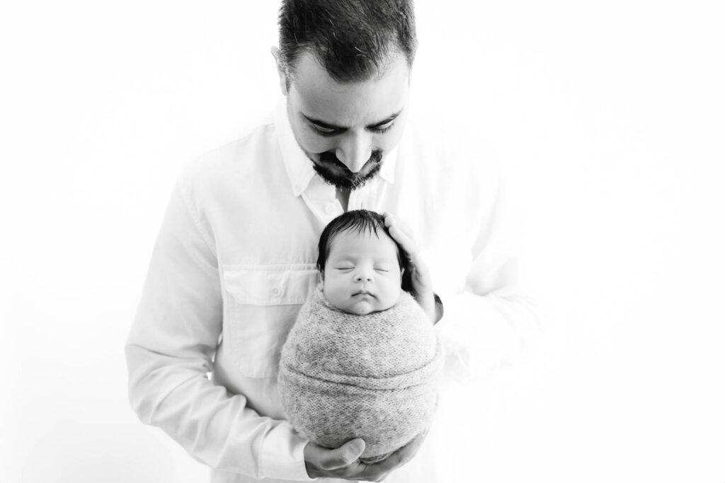 Father Holding His Wrapped Newborn Baby During A Professional Newborn Photography Session In Dallas