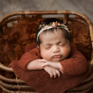 Sleeping newborn posed in a woven basket during a professional newborn photography session by Dallas newborn photographer Lily Hayes.