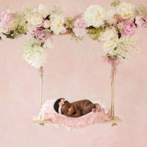 Sleeping newborn on a floral swing during a fine art newborn photography session in Dallas.