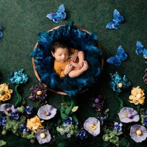 Sleeping newborn surrounded by handcrafted butterflies and flowers during a luxury newborn photography session in Dallas.