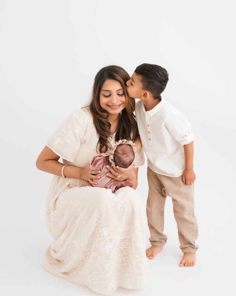 Mother Holding Her Newborn Daughter While Her Son Gently Leans In.