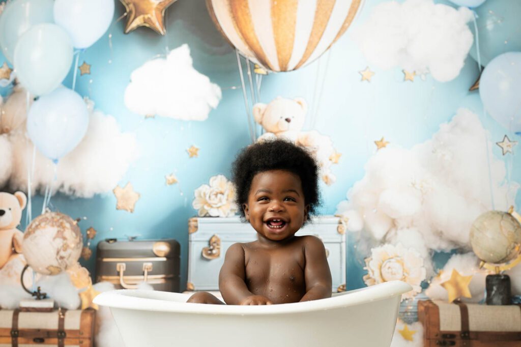 Close-Up Portrait Of A Smiling Baby During A First Birthday Milk Bath Session In Dallas.