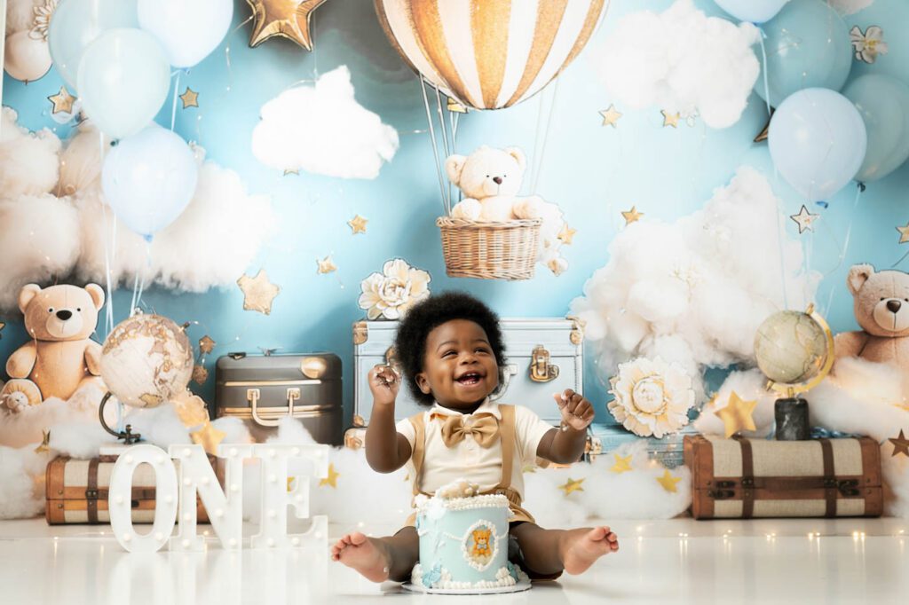 Baby Sitting In Front Of A Blue Hot Air Balloon Cake Smash Backdrop In Dallas.